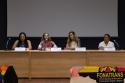 Sentadas em uma mesa comprida com um telão no fundo, da esquerda para direita estão: Joyce Alves, Dani Balbi, Ariela Nascimento e Theo Silveira