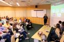 Foto do auditório do INI sentadas ouvindo a palestra da vice-diretora de Gestão do INI, Solange Siqueira, que veste calça e camisas pretas.