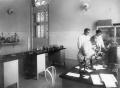 Oswaldo Cruz observa um microscópio ao lado de seu filho Bento e de Burle de Figueiredo, no interior de um dos laboratórios do Castelo de Manguinhos, 1910 (Acervo da Casa de Oswaldo Cruz)